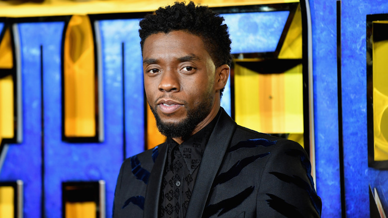 Chadwick Boseman in front of signage for Black Panther