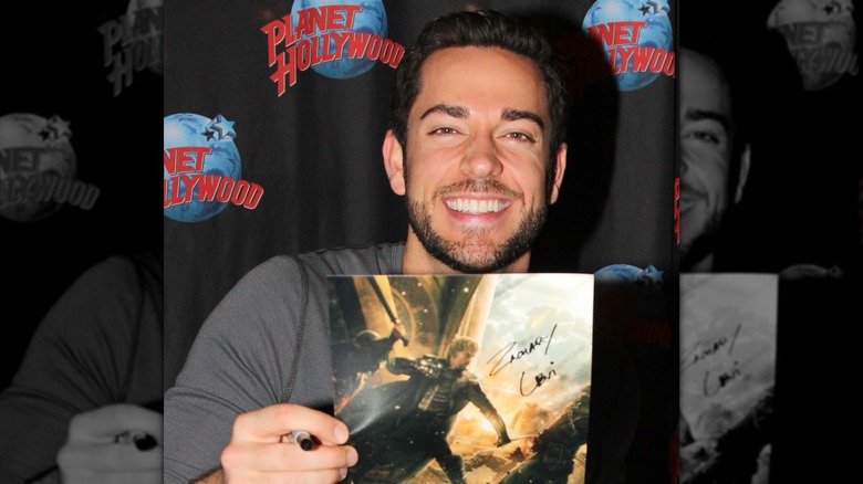Zachary Levi holding up his autograph