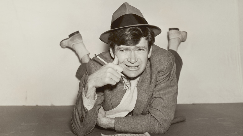 A young Buddy Ebsen doing a crossword puzzle while lying on the floor, holding a pencil