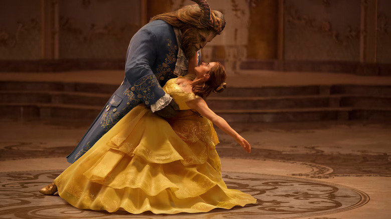 Belle, wearing a flowing yellow dress, dips backwards as she looks into the eyes of the Beast as they dance in a ballroom in "Beauty and the Beast"