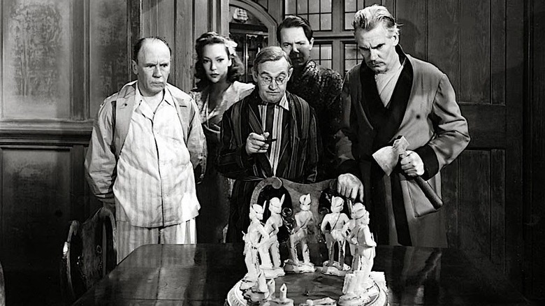 A group of people starring at broken figurines in "And Then There Were None."