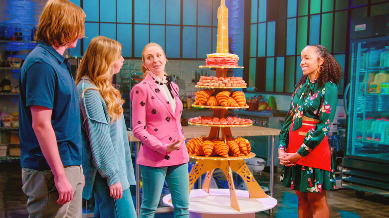 People standing around an Eiffel Tower of pastries in Bake Squad (2021)