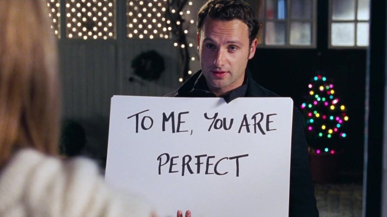 Mark stands outside and holds a sign that says to me, you are perfect in Love Actually (2003)