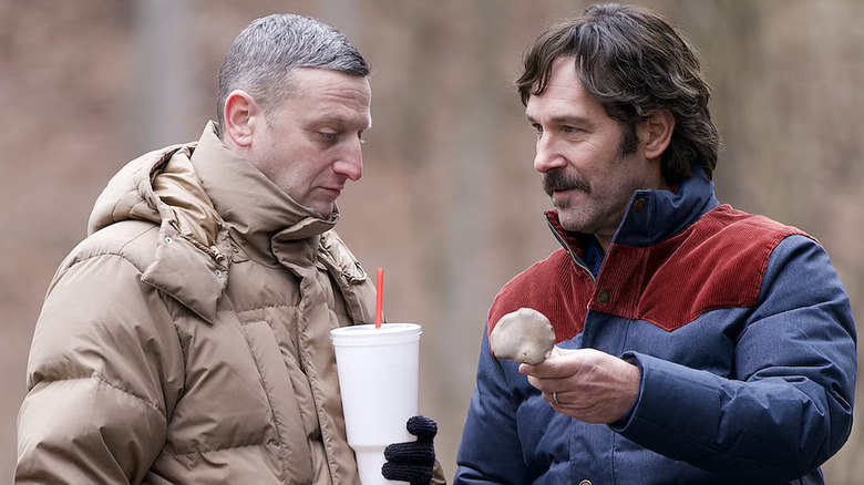 Craig holding a fountain drink while Austin shows him a mushroom in the woods