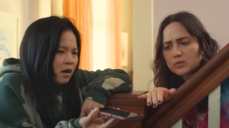 couple Angela and Lee sitting at the foot of their stairs and listening to someone on speaker phone