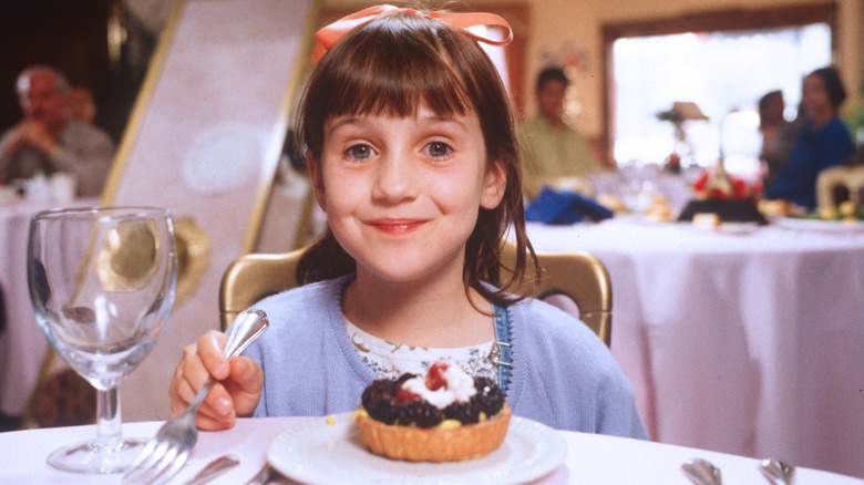 Matilda smiling at a dinner table in "Matilda"