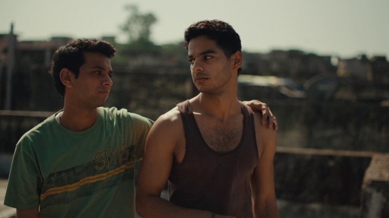 Chandan exchanging a serious glance with Shoaib with an arm around his shoulder in Homebound