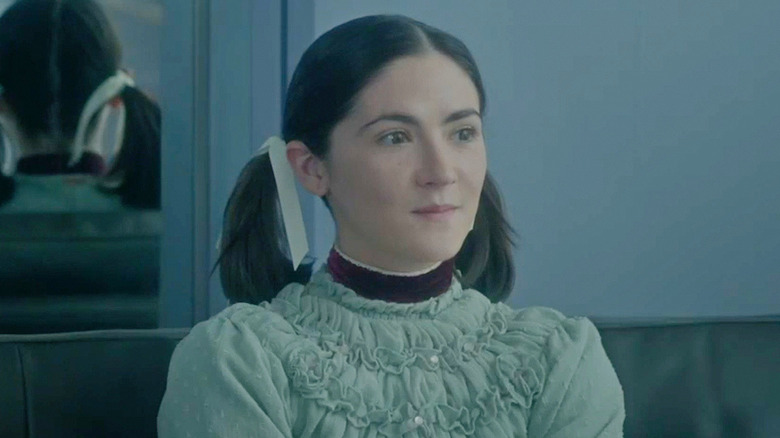 Esther sitting on a couch in "Orphan: First Kill" (2022)