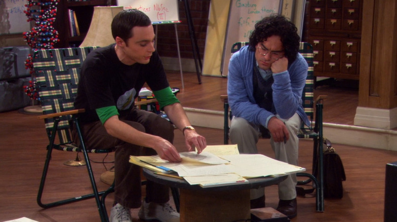 Sheldon and Leonard looking at papers on a table in The Big Bang Theory (2007)