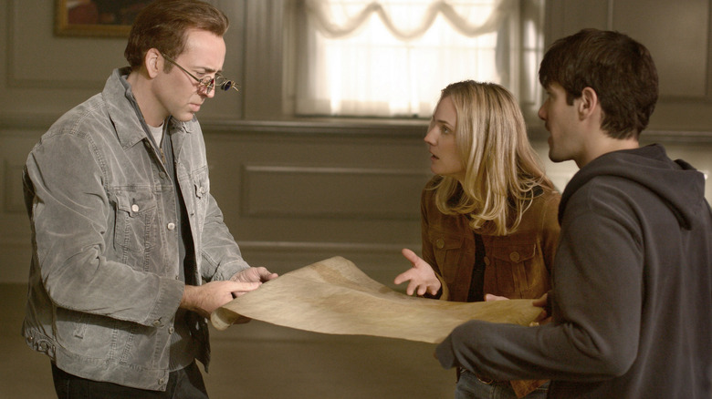 Ben, Abigail, and Riley examining a document in National Treasure (2004)