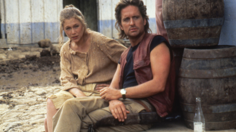Joan and Jack sitting near barrels in Romancing the Stone (1984)