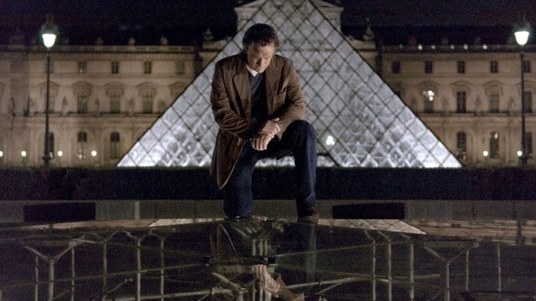 Robert kneels down with the Louvre behind him in The Da Vinci Code (2006)