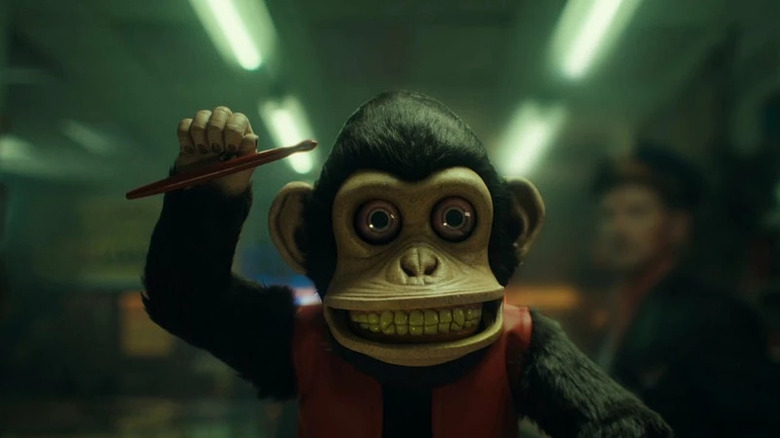 Toy monkey with drumstick in air in The Monkey