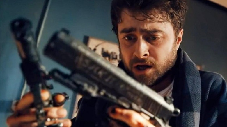 Miles looks at the guns on his hands in Guns Akimbo