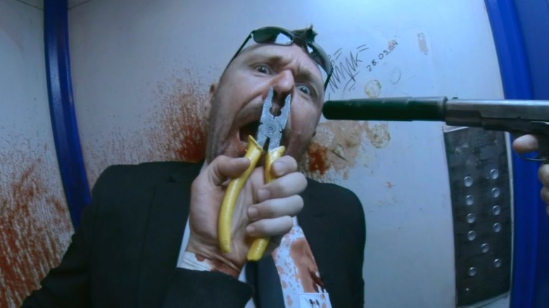 Henry golds a man with plyers on his nose in Hardcore Henry