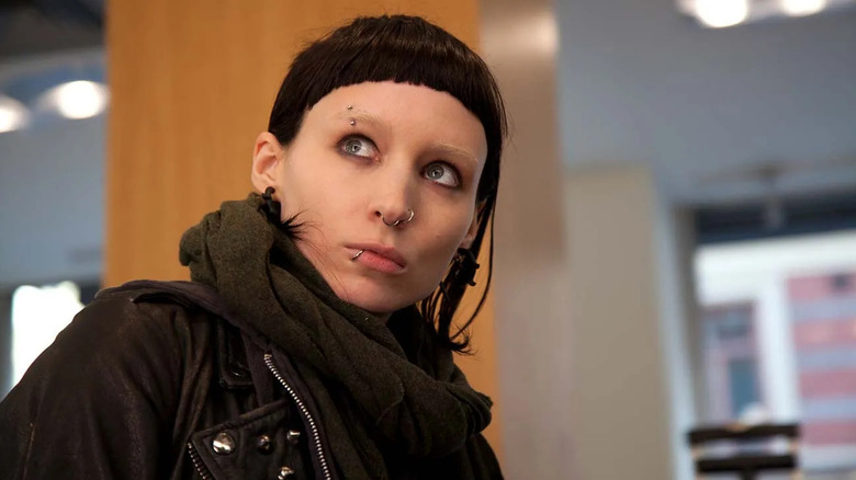 Lisbeth with short hair and face jewelry looking over her shoulder in The Girl with the Dragon Tattoo