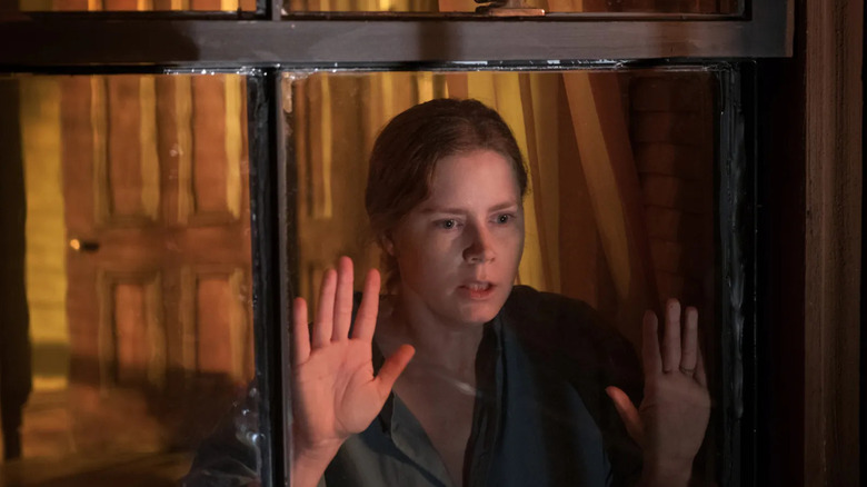 Anna peering out of the window in The Woman in the Window
