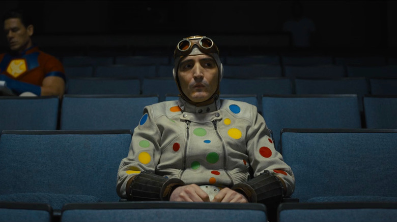 Polka-Dot Man sitting in an auditorium with Peacemaker in the background in "The Suicide Squad"