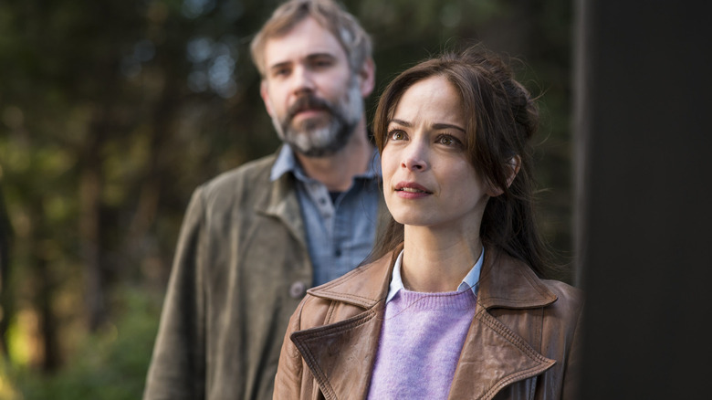 Karl and Cassandra talk stand at a doorway and talk to a resident in Murder in a Small Town