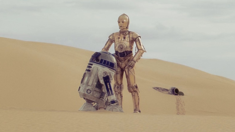 R2-D2 and C-3PO standing together on the sands of Tatooine in 