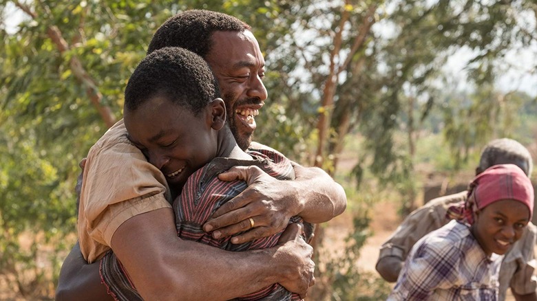 Kamkwamba and his father embrace in the field in The Boy Who Harnessed the Wind