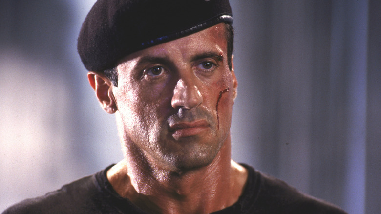 John Spartan looking stoic in a hat, a fresh cut on his cheek, in Demolition Man (1993)