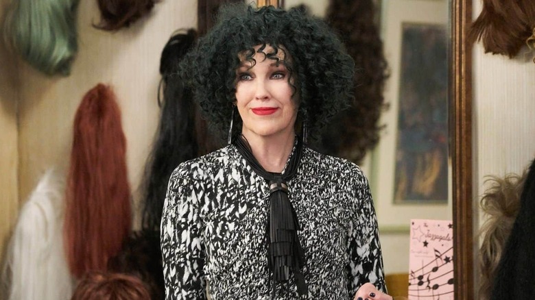 Moira Rose standing in front of her wall of wigs in "Schitt's Creek"