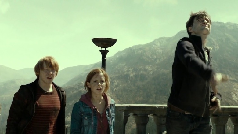 Ron and Hermione watching Harry throw the broken Elder Wand off a cliff in Harry Potter and the Deathly Hallows Part 2