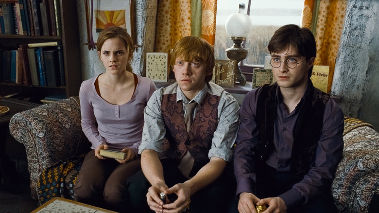 Hermione Ron and Harry sitting on a couch at the Burrow looking shocked in Harry Potter and the Deathly Hallows - Part 1