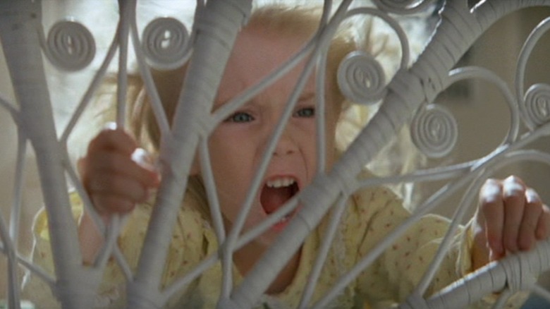 Heather O'Rourke as Carol Anne in Poltergeist screams and holds on to her bed