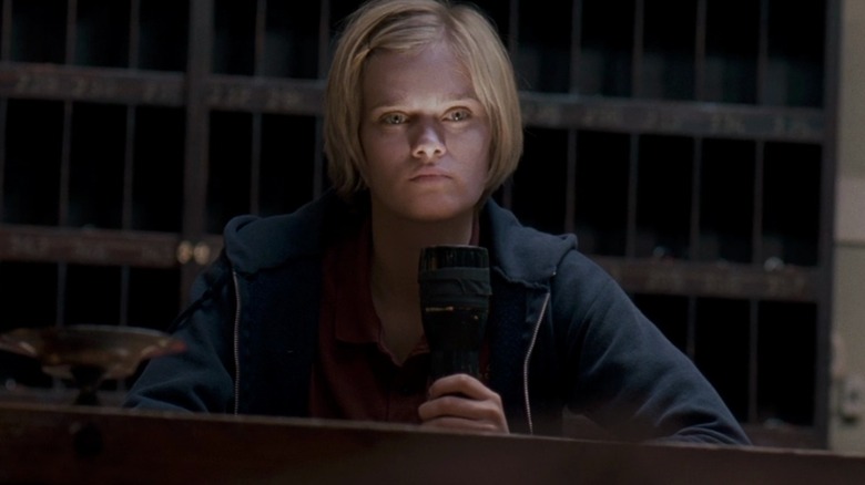 Sara Paxton as Claire lighting her face with a flashlight in The Innkeepers