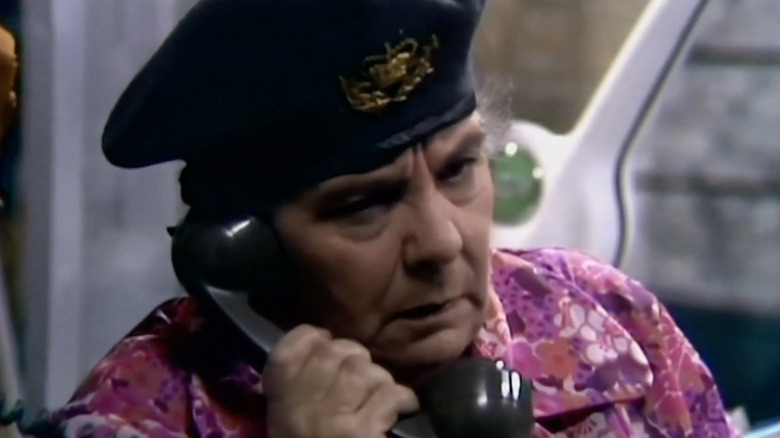 Magi Post Mathias looking grouchy on the phone in Pobol y Cwm