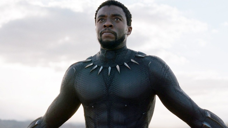 An unmasked Black Panther spreading his arms in "Black Panther"