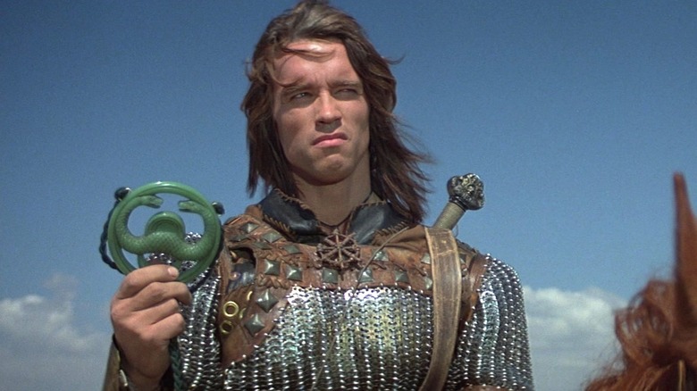 Conan holding a snake symbol in Conan the Barbarian
