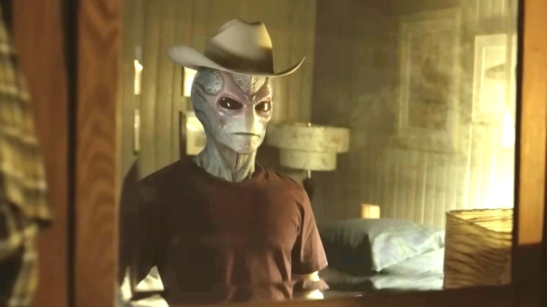 Harry in alien form, wearing a cowboy hat and looking in a mirror in "Resident Alien" (2021)