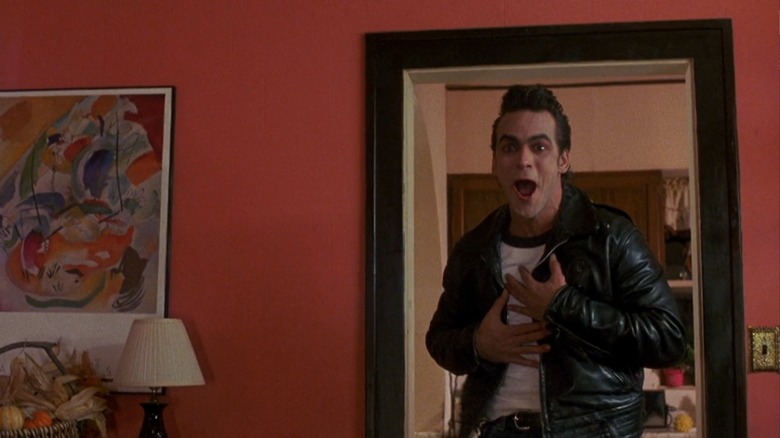 Robert Rusler as Richard Lawson, a greaser ghost, grins and clutches his chest in Sometimes They Come Back