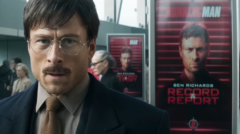 Glen Powell as Ben Richards in disguise, standing in front of a photo of himself from The Running Man