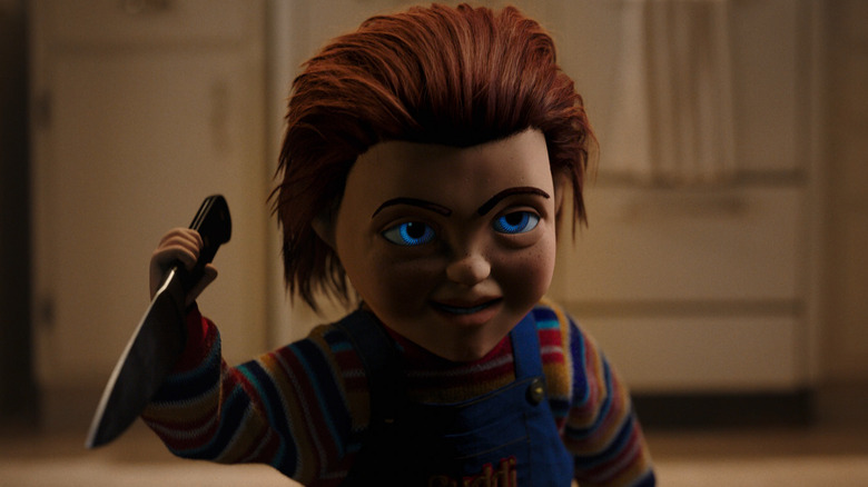 Chucky holds a knife while smiling sinisterly in Child's Play (2019)