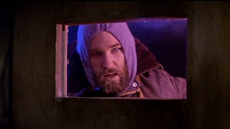 Kurt Russell as RJ MacReady in The Thing, peering in a window
