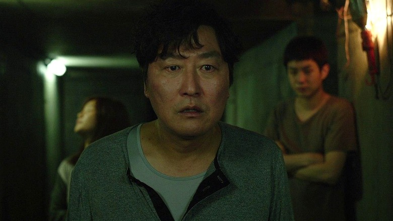 Ki-taek nervously walking in the basement with his kids