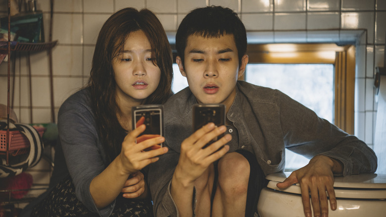 Ki-jung and Ki-woo looking at phones