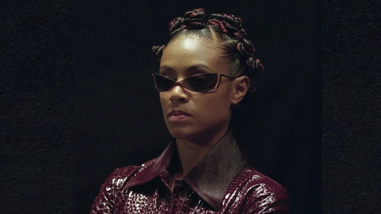 Niobe wears a purple leather jacket, with triangular shades, in "The Matrix Reloaded"