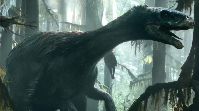 The feathered Therizinosaurus stalks through the green swamp in "Jurassic World: Dominion"
