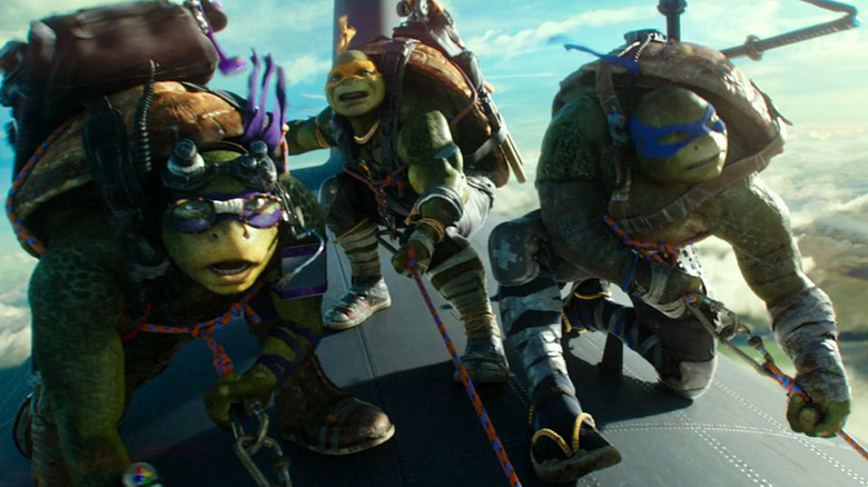 Donatello, Michelangelo, and Leonardo hanging on to a plane in Teenage Mutant Ninja Turtles: Out of the Shadows