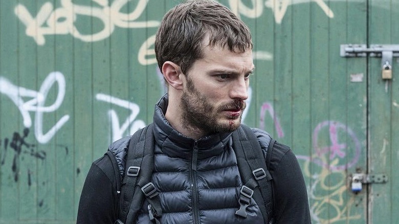 Paul with blood on his face in a black vest looking troubled on The Fall