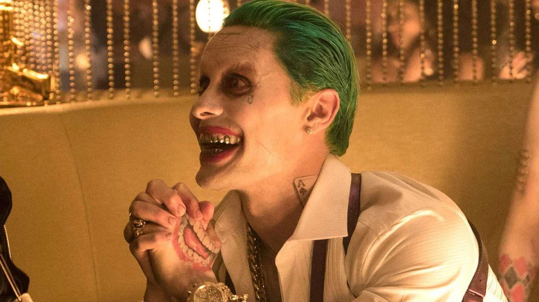 The Joker smiling in a glitzy, gold booth in Suicide Squad (2016)