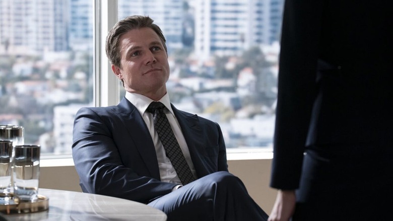 Ted sitting at his desk talking to somebody on Suits LA