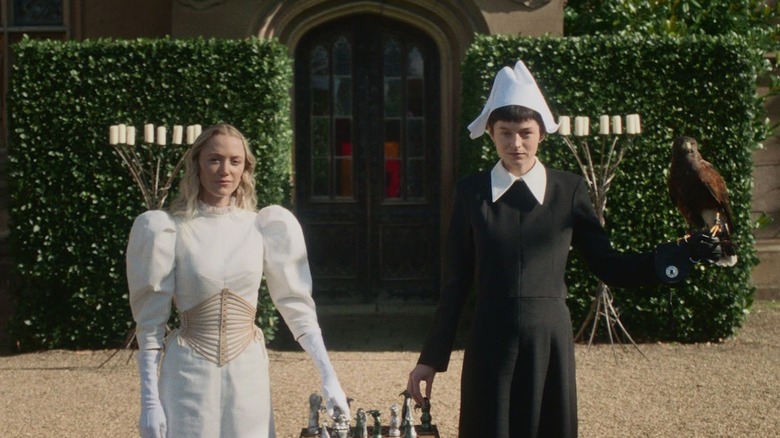 Cherry and Hero standing by a chess set outside in 