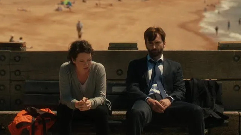 Ellie Miller and Alex Hardy sit on the pier with their backs to the beach in "Broadchurch" (2013-2017)