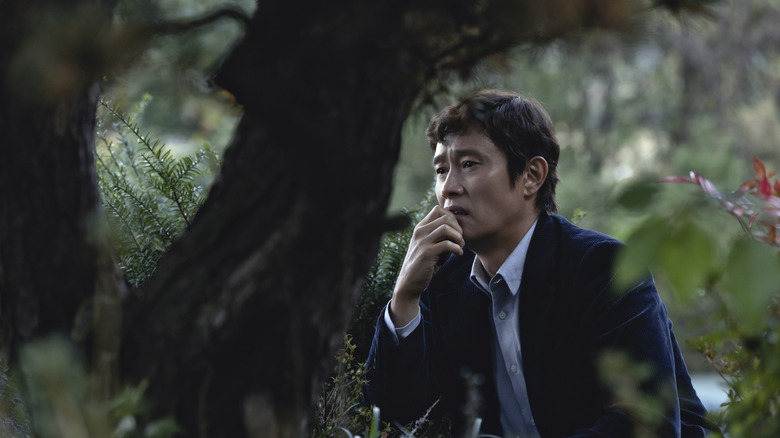 Man-su watching a target in "No Other Choice" (2025)